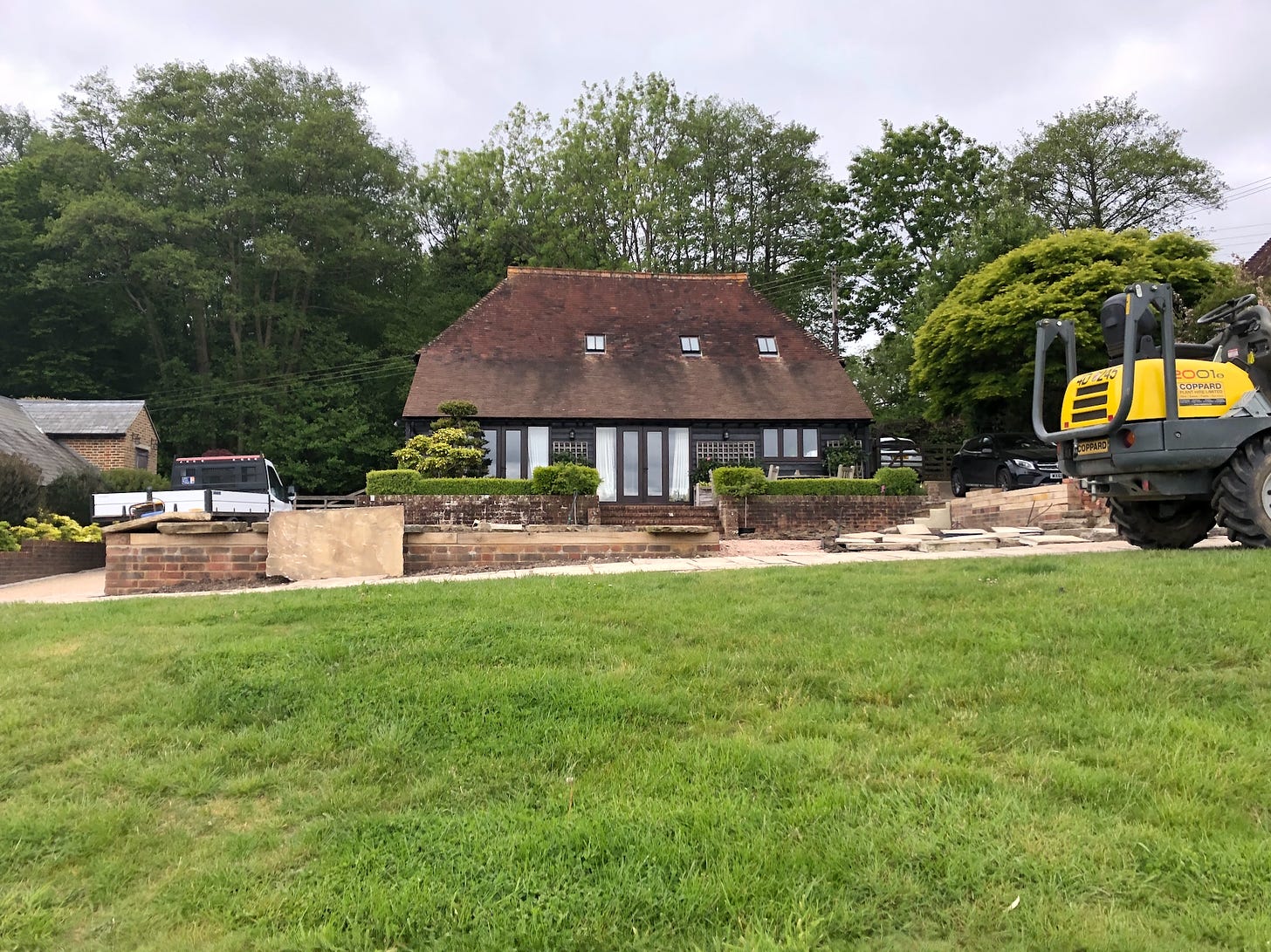 a building site in a garden in the countryside with a yellow digger