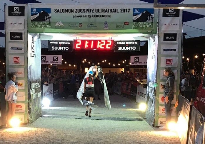 Lisa crossing the finish line at ZUT holding a finish banner in her hands