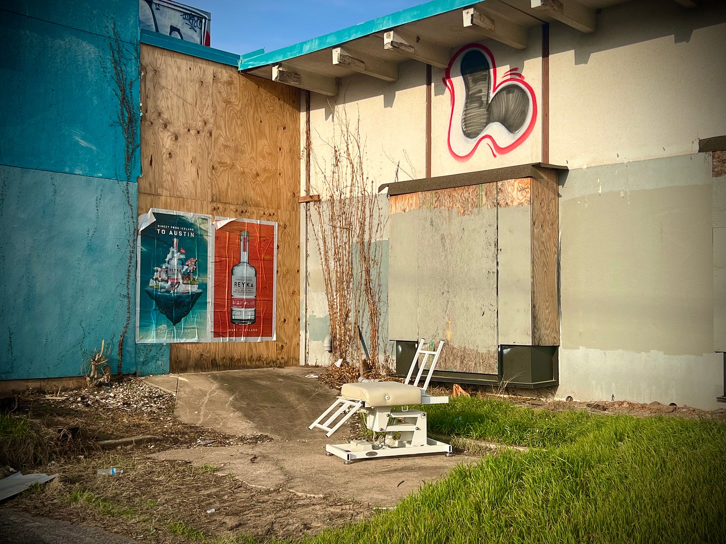 Medical chair outside an abandoned and boarded-up building