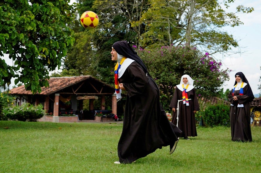 Several nuns play with a soccer ball.