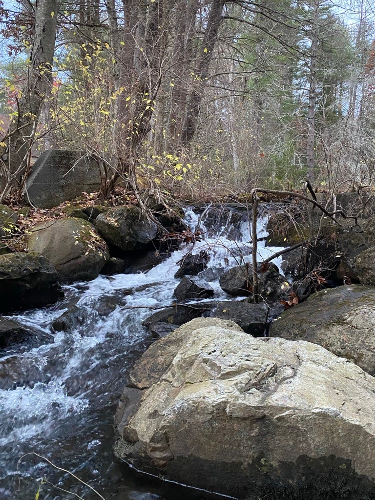 a partially frozen waterfall in a rocky stream.