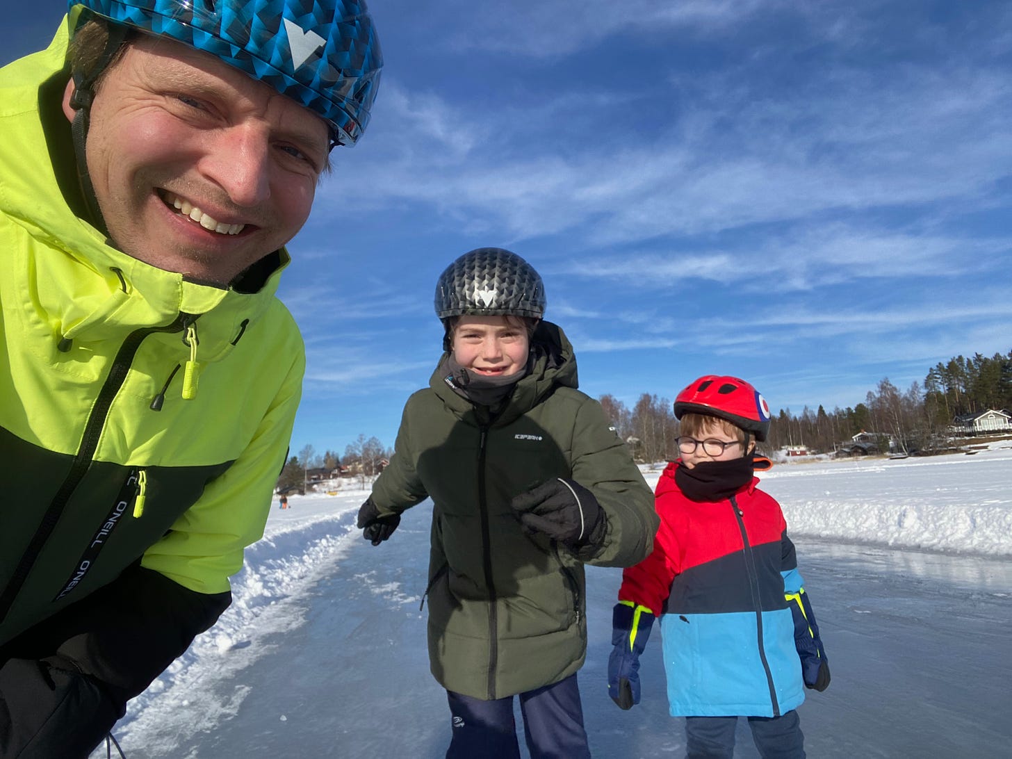 The author and his two sons on a frozen lake in Sweden, wearing helmets and snow jackets