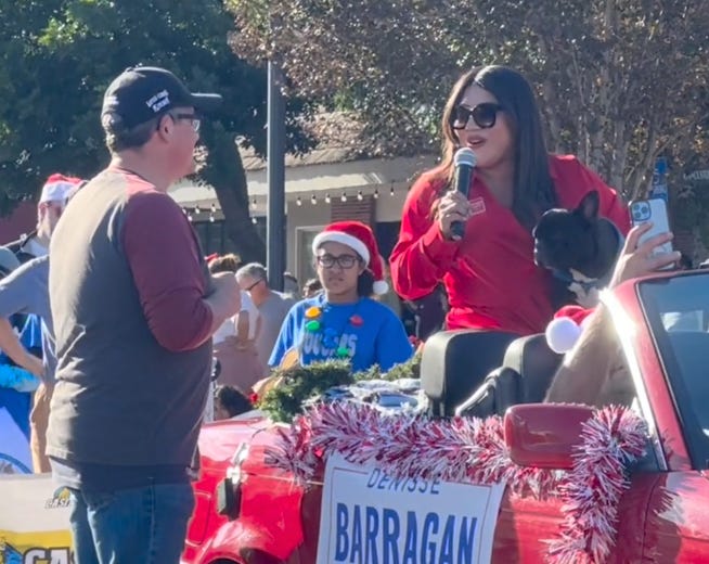 Don Hein, left, listens to Denisse Barragan introduce herself and her dog, Jackson, during the Vista Christmas Parade on Dec. 2 to fill time. Another emcee made a comment saying residents should vote for Barragan in the District 3 race because she brought her dog sparking the potential for the Vista Chamber of Commerce to lose its grant from the city to host the parade. Steve Puterski image