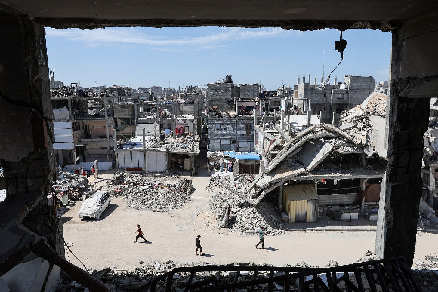 Palestinians walk near rubble of houses in Khan Younis