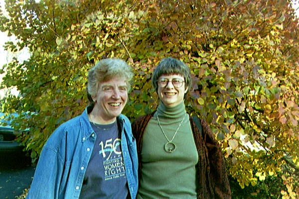 Two women standing in front of a tree with fall colors