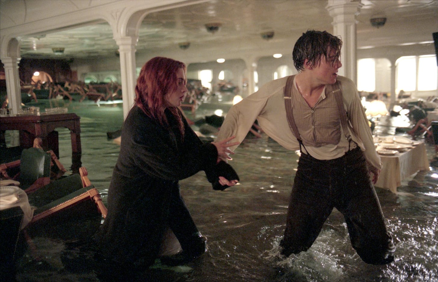 A screenshot from Titanic, showing Jack and Rose wading through water in the ship's interior.