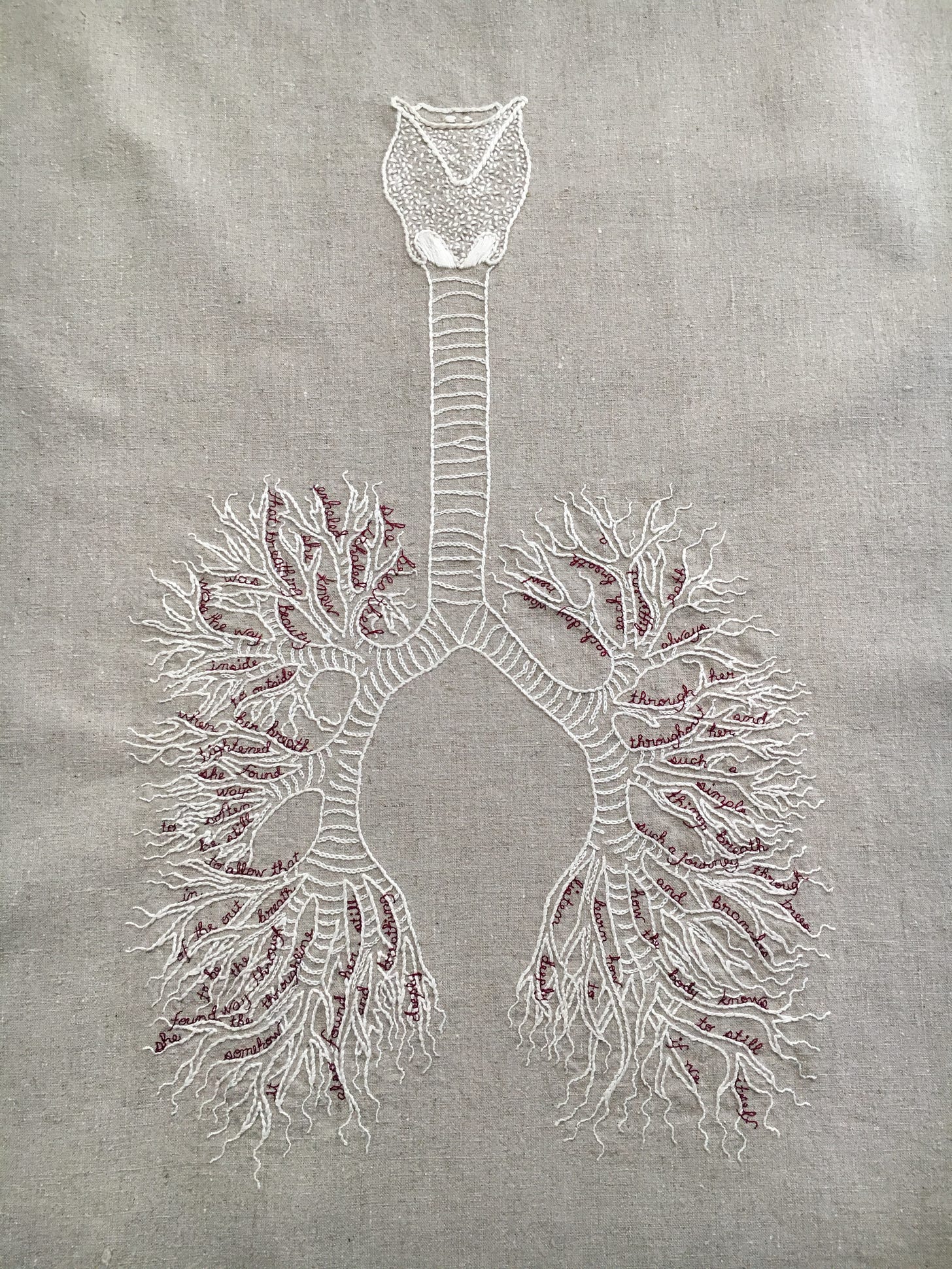 An embroidery on a pale natural linen. There is a bone white diagram of a vocal apparatus, trachea, and bronchi/lungs. In between the branches of the bronchioles are small words embroidered in cursive in thin burgundy thread. They read: she breathed. Inhaled. exhaled. she knew. that breathing. was beauty. was the way. inside. to outside. when her breath. tightened. she found. ways. to soften. be still. to allow that. in. of the out. breath. to be. the. way through. she found the throughline. somehow. it. also found her. still. and   breathing. deeply. each day was. new. each breath. a. different. path. always. through her. and. throughout her. such a. simple. thing, breath. such a journey. through. trees. and. branches. how the body knows. to still. itself. if we learn how. to. listen deeply.