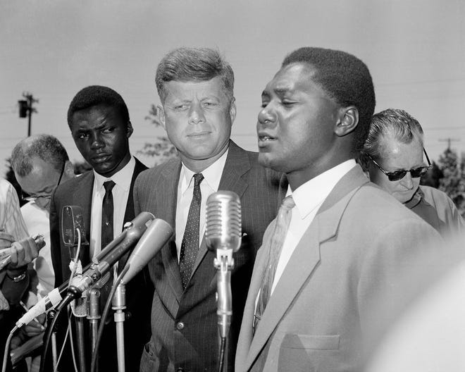 U.S. Sen. John F. Kennedy listens as Tom Mboya, general secretary of the Kenya Federation of Labor, talks to newsmen on the lawn of the Democratic presidential candidate's home at Hyannis Port, Massachusetts, on July 26, 1960. Mboya flew from New York to discuss African problems with the senator.