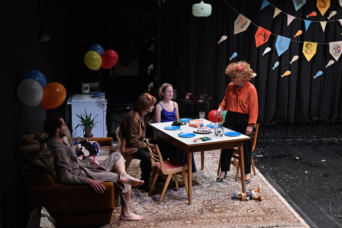 A scene from 52 Hertz - a table is set as if for a family birthday party. There are balloons. The audience is visible on the left hand side..