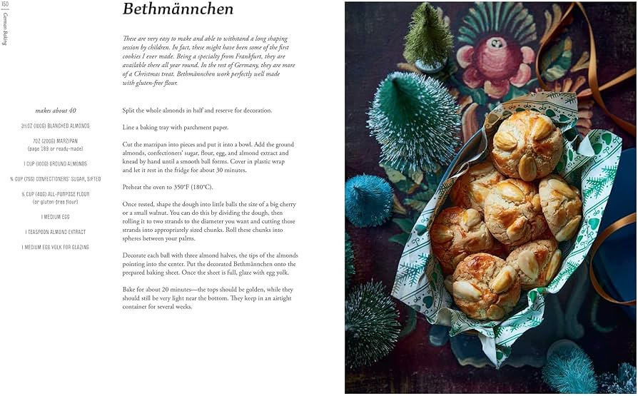 A recipe for Bethmännchen, a German marzipan cookie. The photo is quite moody with all the light aimed at a teatowel-lined basket containing golden buns. Surrounding it are the kind of model fir trees you buy to decorate model railways. 