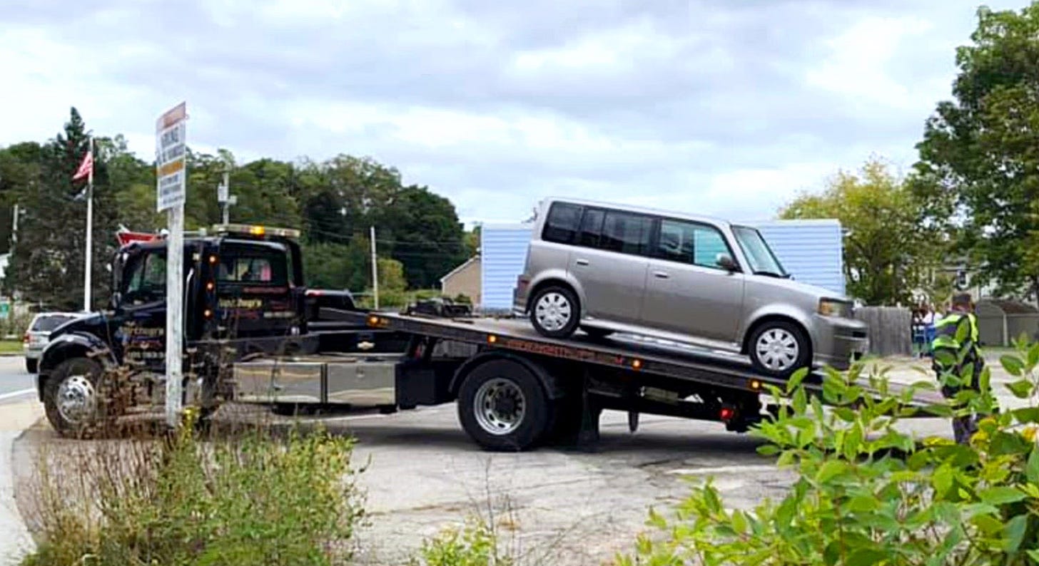 my boxy looking car on the bed of a tow truck