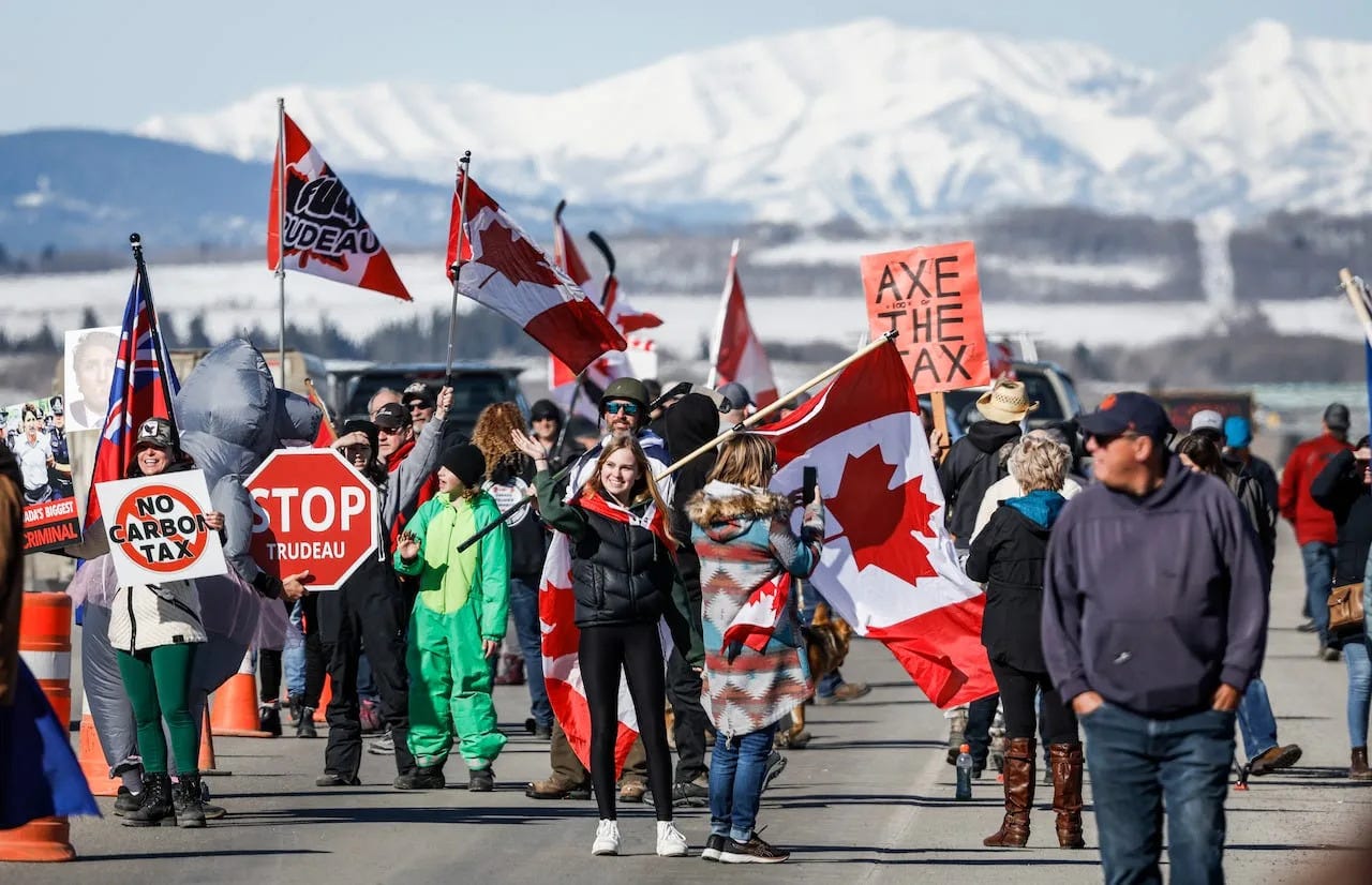 Anti-carbon tax protesters wave signs and chant slogans as they block a westbound lane of the Trans Canada highway near Cochrane, Alta., Monday, April 1, 2024.