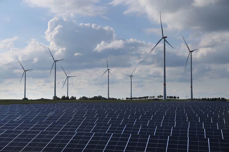 Wind turbines spin behind a solar energy park.