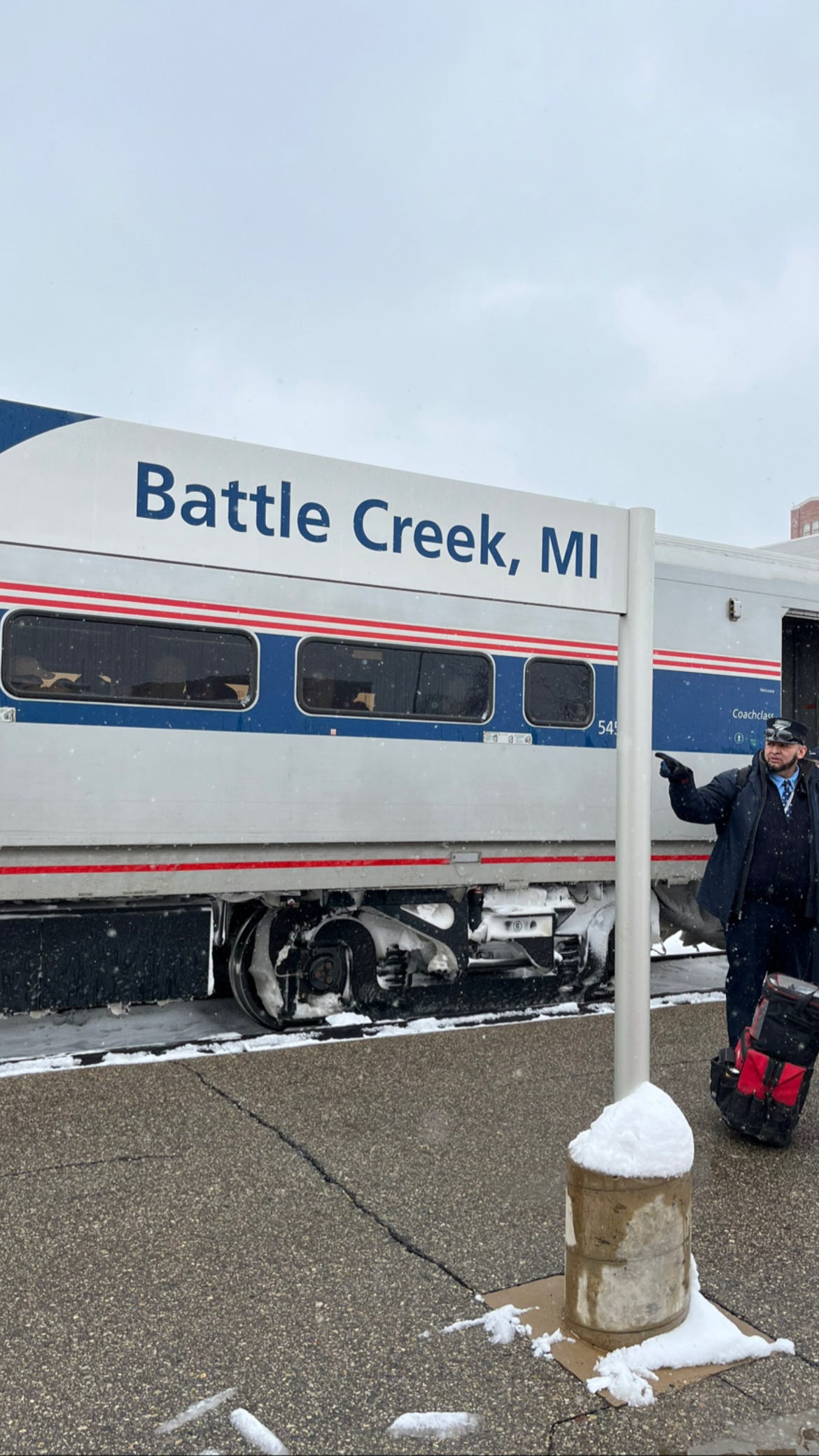 Train conductor stands in front of Amtrak Train stopped at the Battle Creek, Michigan station