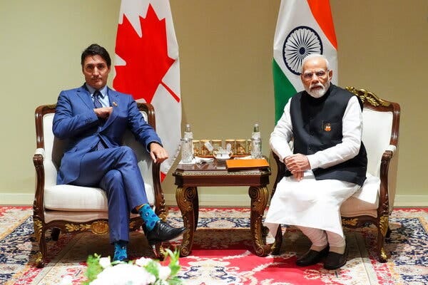 Justin Trudeau and Narendra Modi sit stiffly in ornate chairs, with a small table between them.