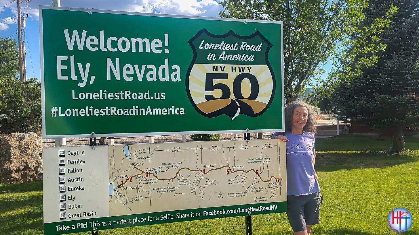 Therese Iknoian, the author, stands in front of a sign in Ely, Nevada designating the Loneliest Road, Highway 50.