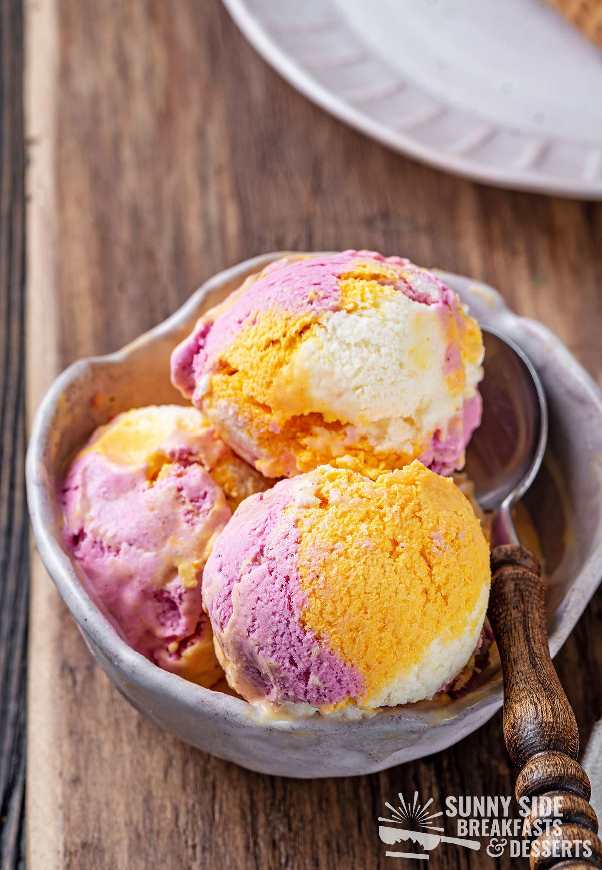 Three scoops of rainbow sherbet in a bowl.