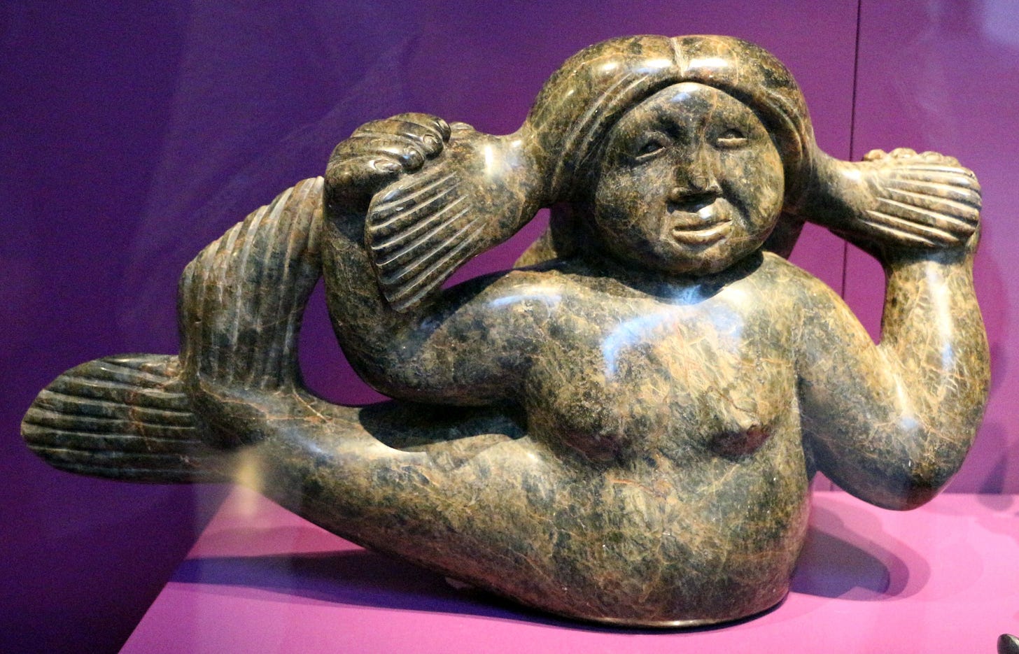 Sculpture of woman with fish tail, holding out her pigtails in both hands.