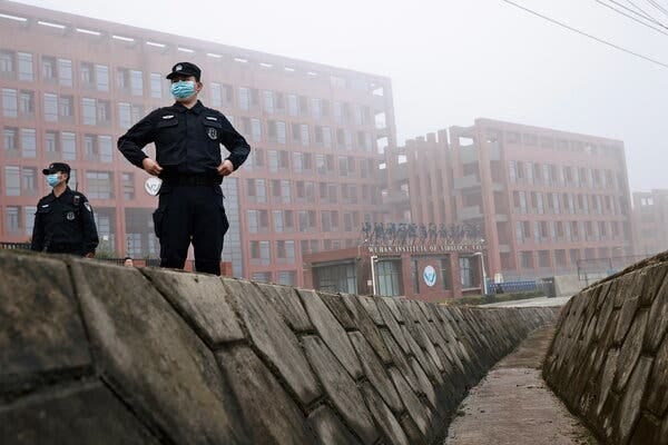 Two men wearing uniforms and masks outside the Wuhan Institute of Virology.