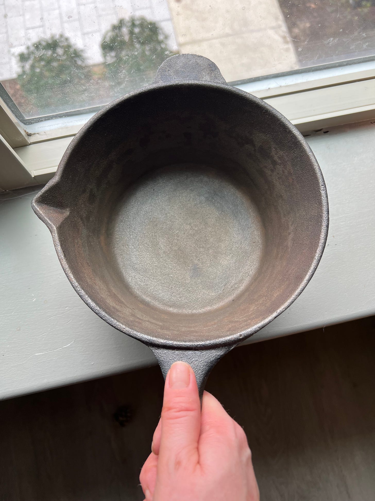 Image of EJW holding a newly cleaned cast iron pot on her windowsill
