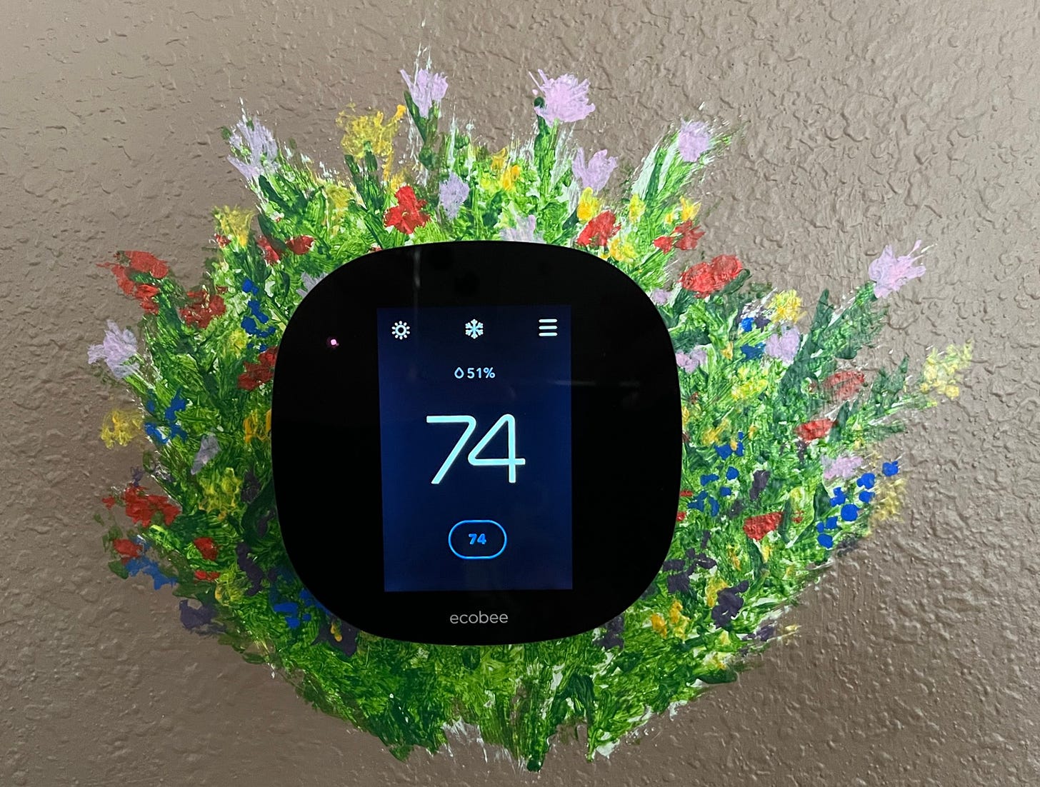 Photo of Ecobee thermostat mounted to wall with colorful, impressionistic flowers painted around the Ecobee device