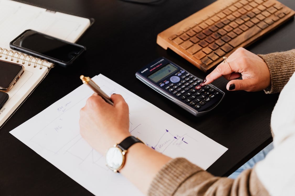 Free Bookkeeper Writing Down on Paper while using Calculator Stock Photo