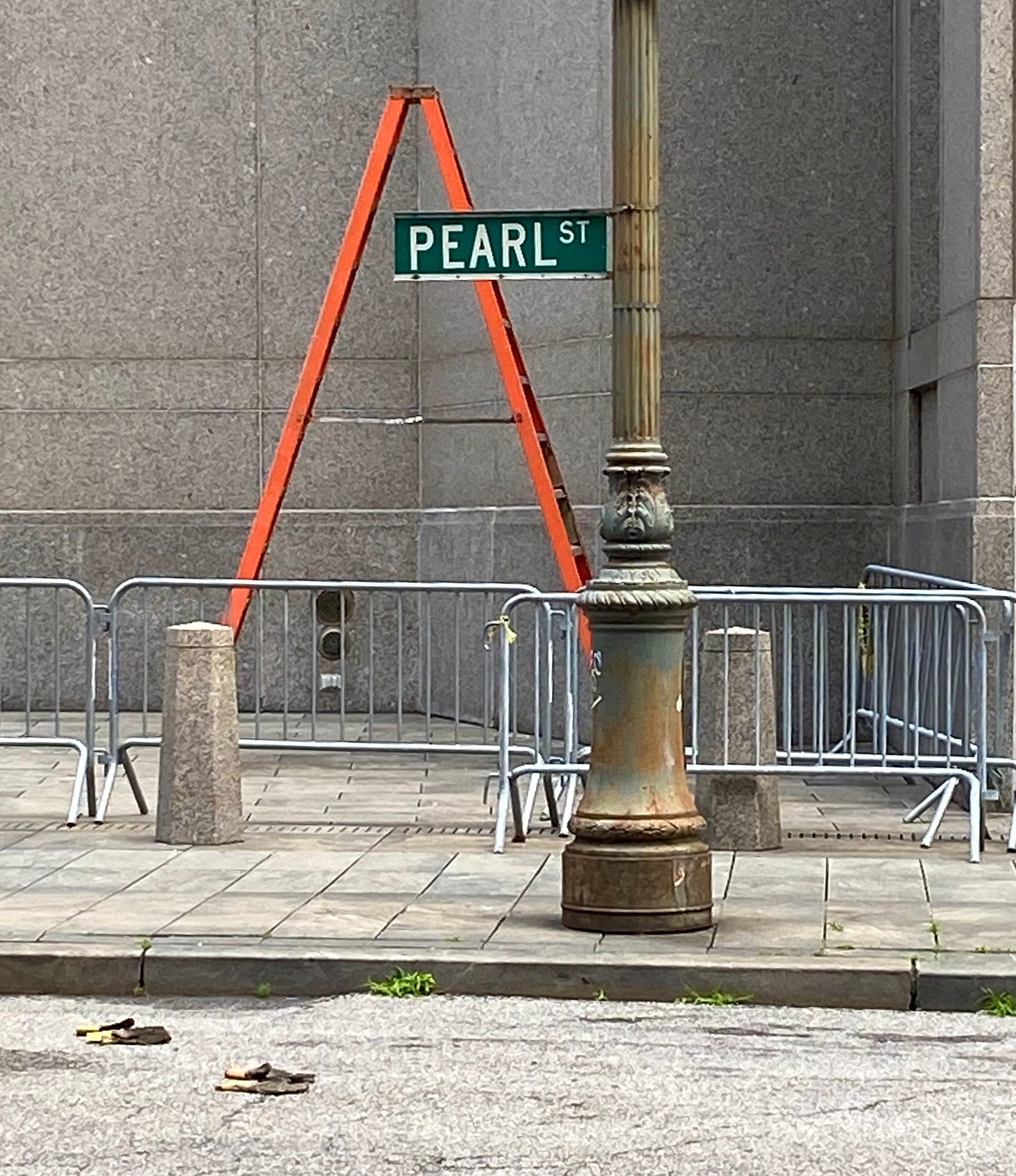 A street sign by the court district for Pearl Street. There is an orange ladder set up behind the post.