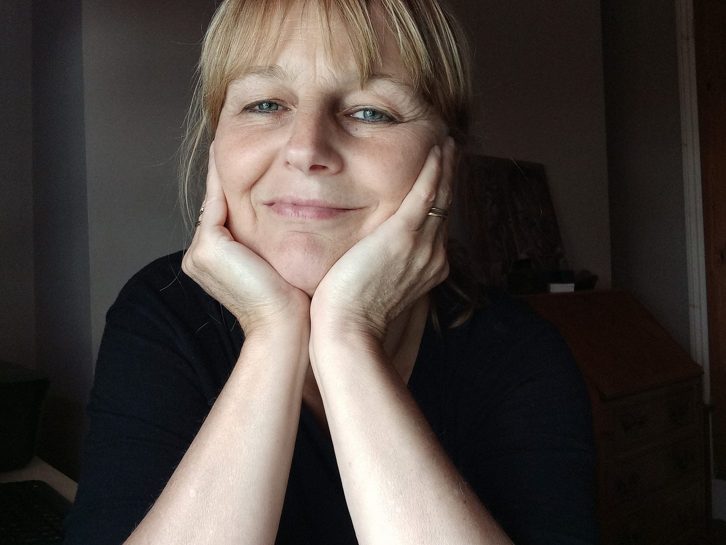 Woman with blond hair resting her head on two hands