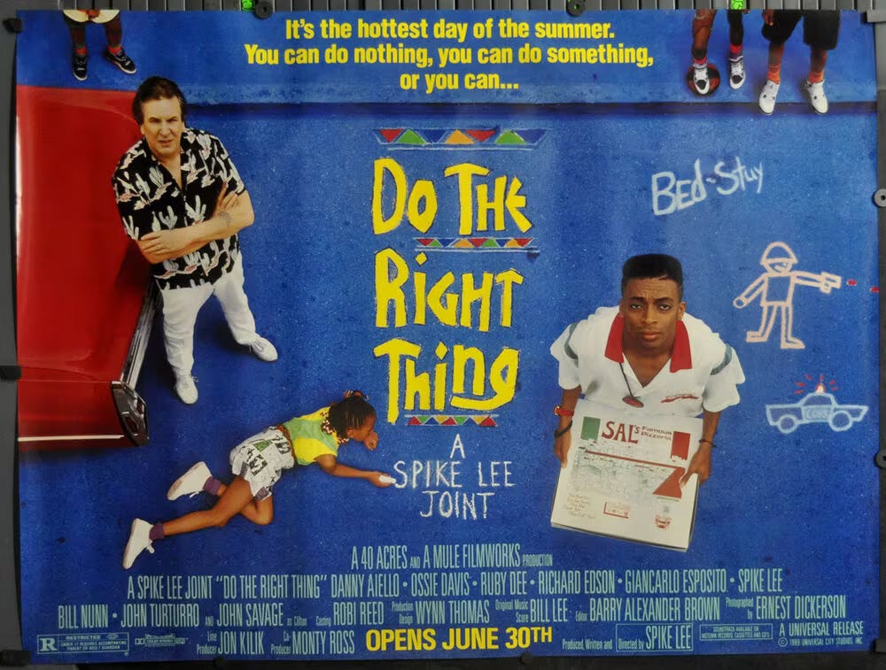 This image shows the one-sheet poster from Spike Lee's 1989 film Do the Right Thing. Protagonists Sal (played by Danny Aiello, left) and Mookie (played by Spike Lee, right) stand on a blue street and look up at the camera while a young Black girl, lying in the street between them, writes the words "A Spike Lee Joint" in chalk. At the poster's top, in yellow lettering, appear the words, "It's the hottest day of the summer. You can do nothing, you can do something, or you can...," leading into the movie's title. The film's credits appear at the bottom, along with the words "Opens June 30th."