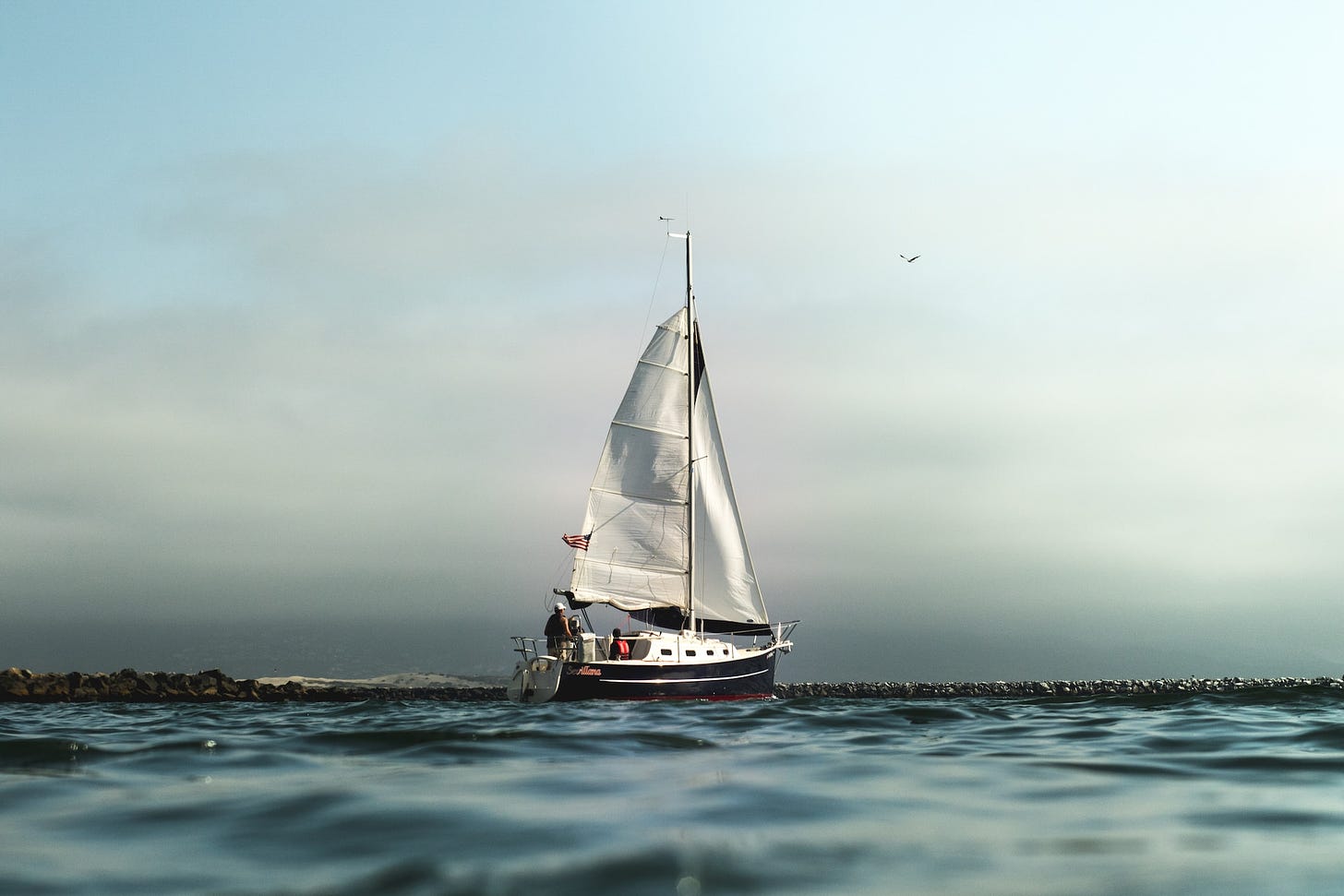 A sailboat sailing on a calm ocean, with a clear blue sky above. The image represents the journey of life, and the importance of embracing the unknown.