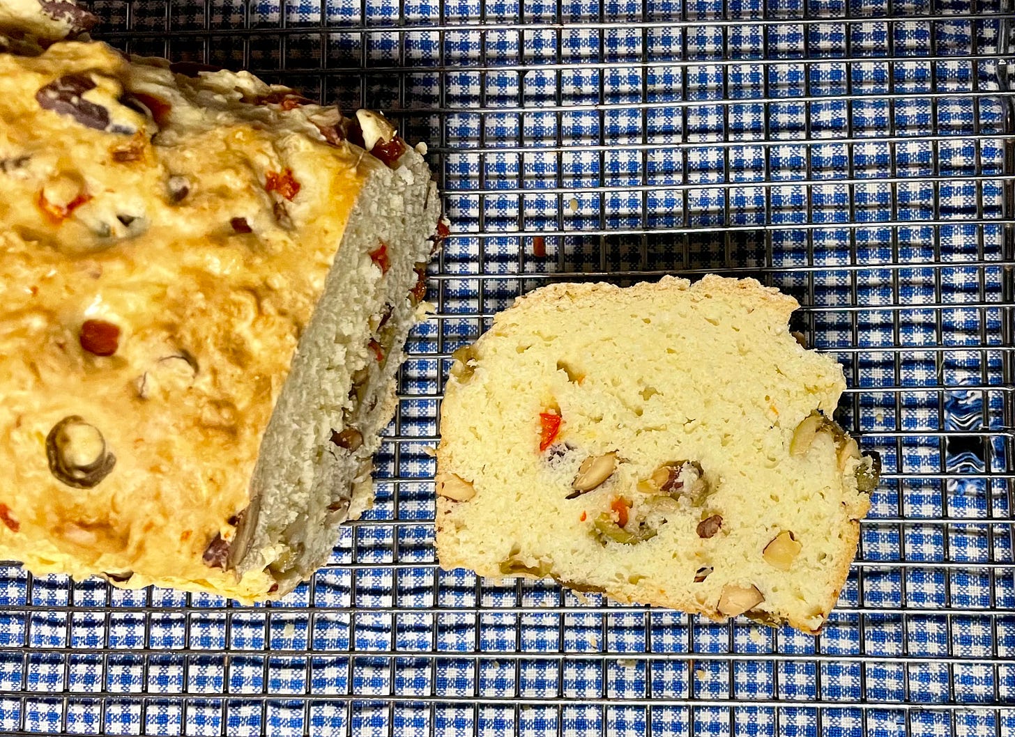 a loaf and slice of olive bread on a blue checked towel