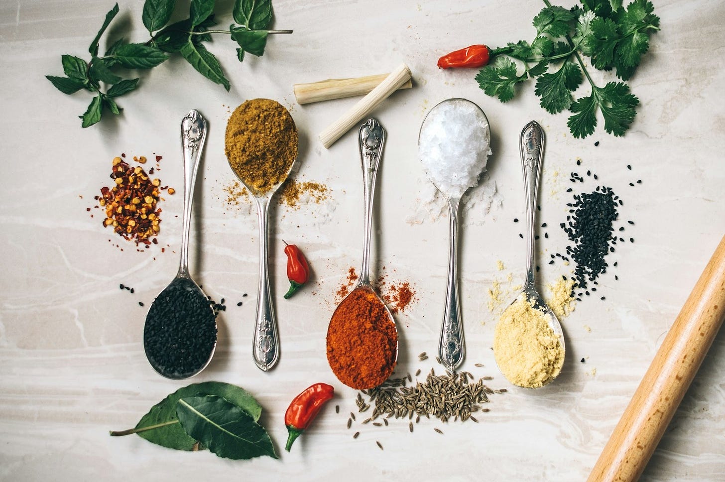 five gray spoons filled with assorted-color powders near chilli