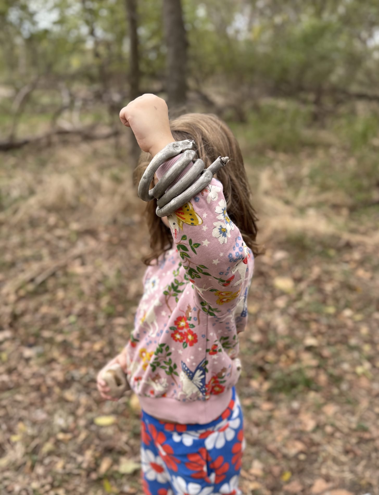 Young girl in unicorn sweatshirt holding up power fist with metal coil around her wrist