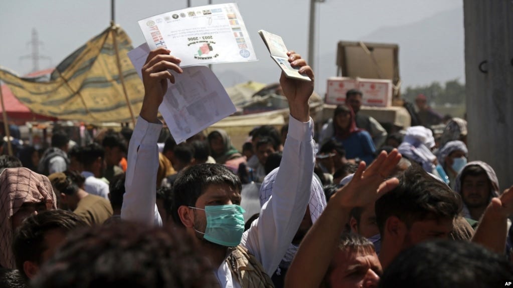 FILE — Hundreds gather, some holding documents, near an evacuation control checkpoint on the perimeter of the Hamid Karzai International Airport, in Kabul, Afghanistan, Aug. 26, 2021.