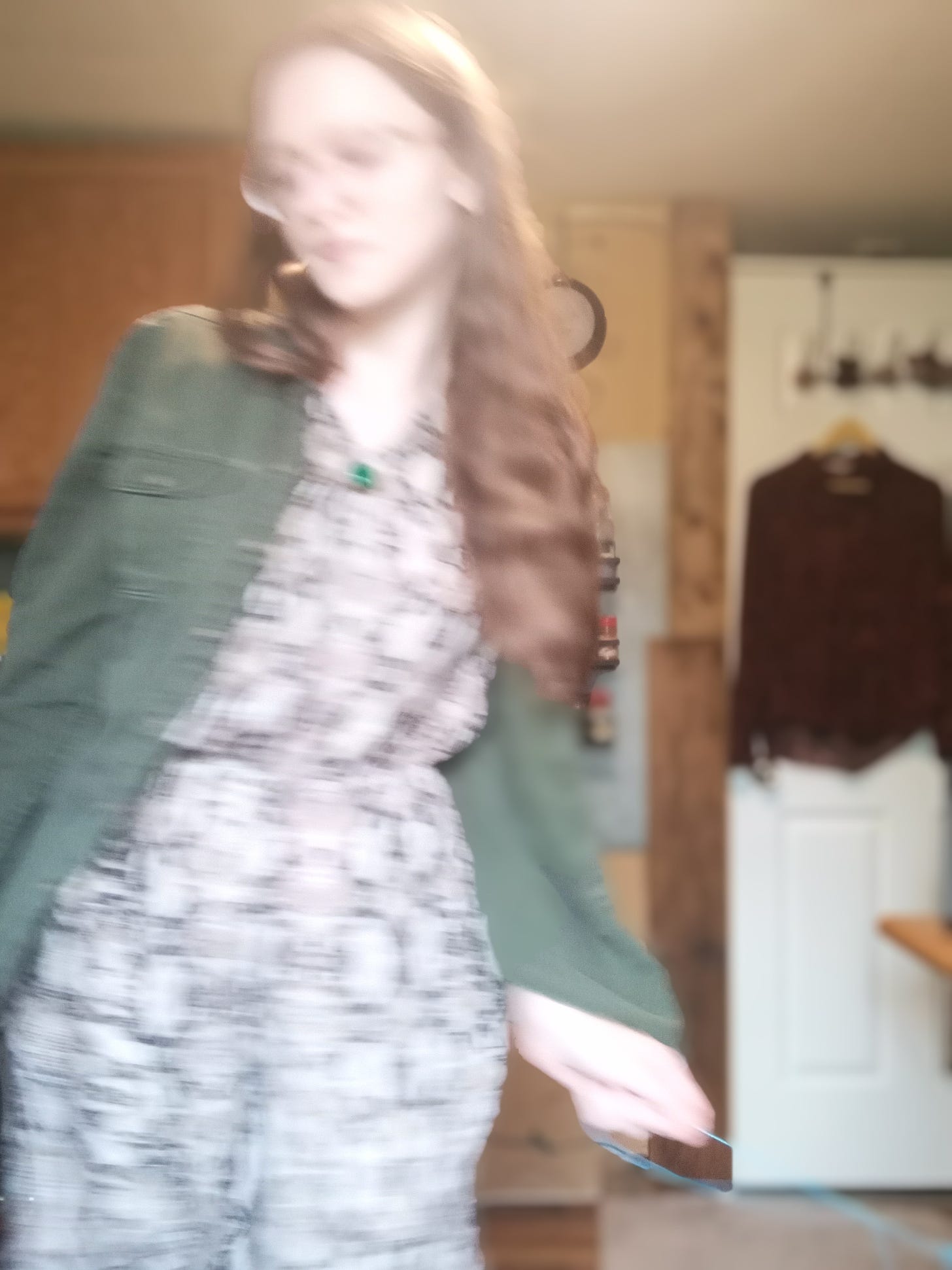 Kandi Zeller (she/her), a white woman with long reddish brown hair, twirls as part of an interpretive dance, resulting in a blurry picture. She is holding a light blue ribbon that is twirling with her.