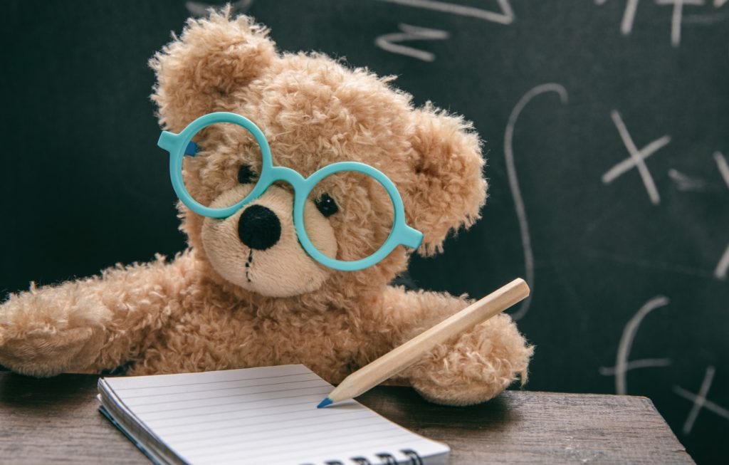 Math test. Cute teddy wearing glasses and black chalkboard
