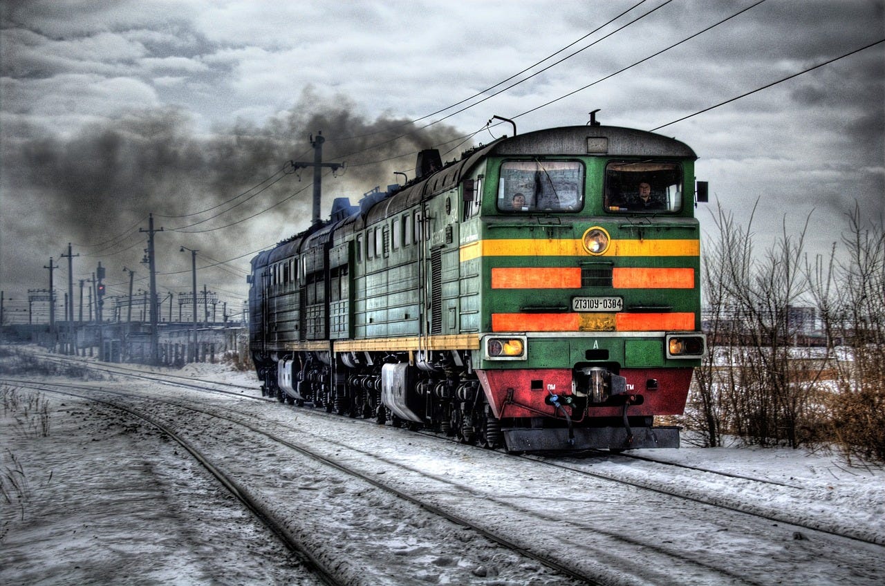 Small green steam train in a grey landscape.