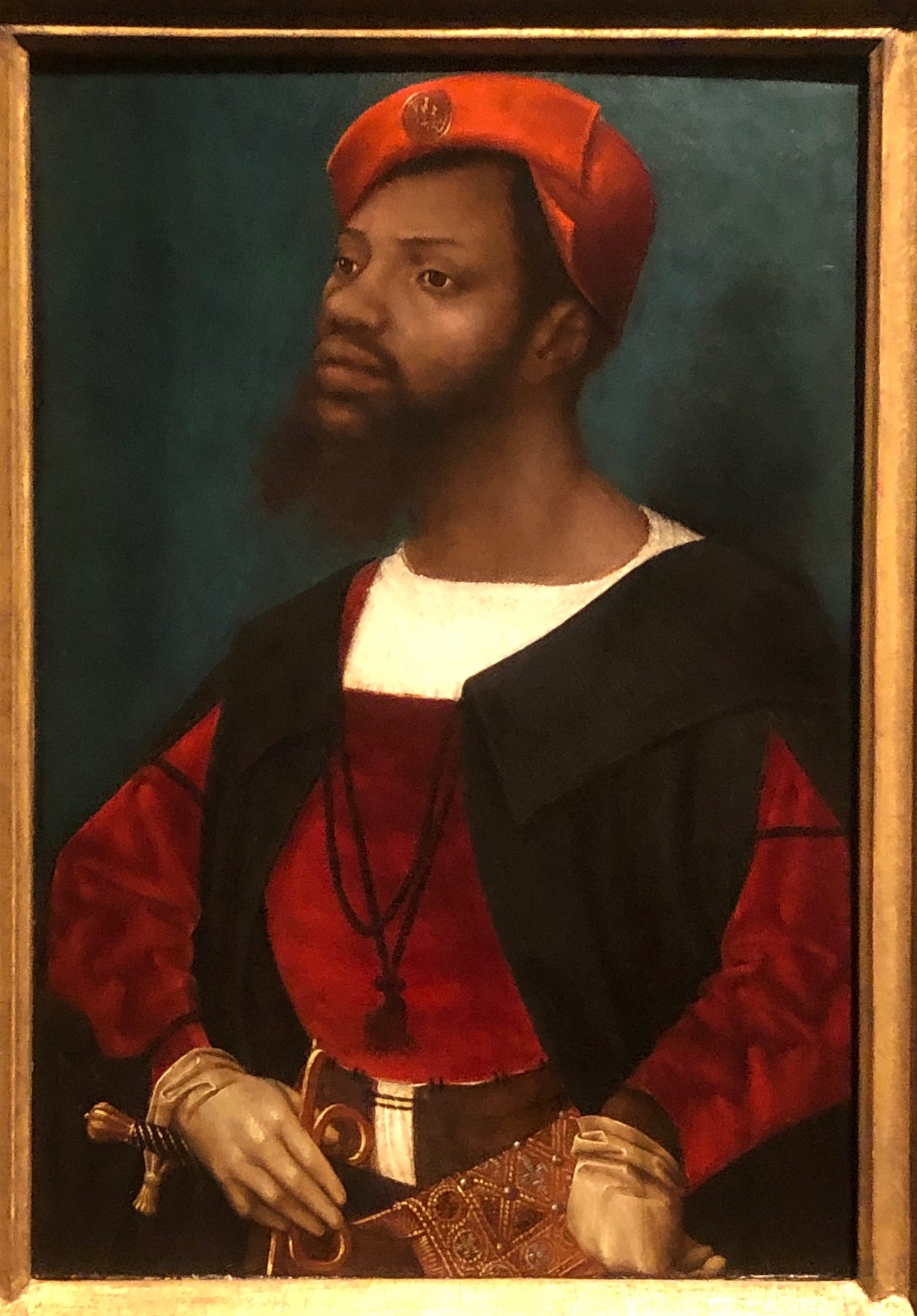 Portrait of a Black man in a cap with a badge on it, an elegant outfit, gloves, and a sword and jewelled golden scabbard.