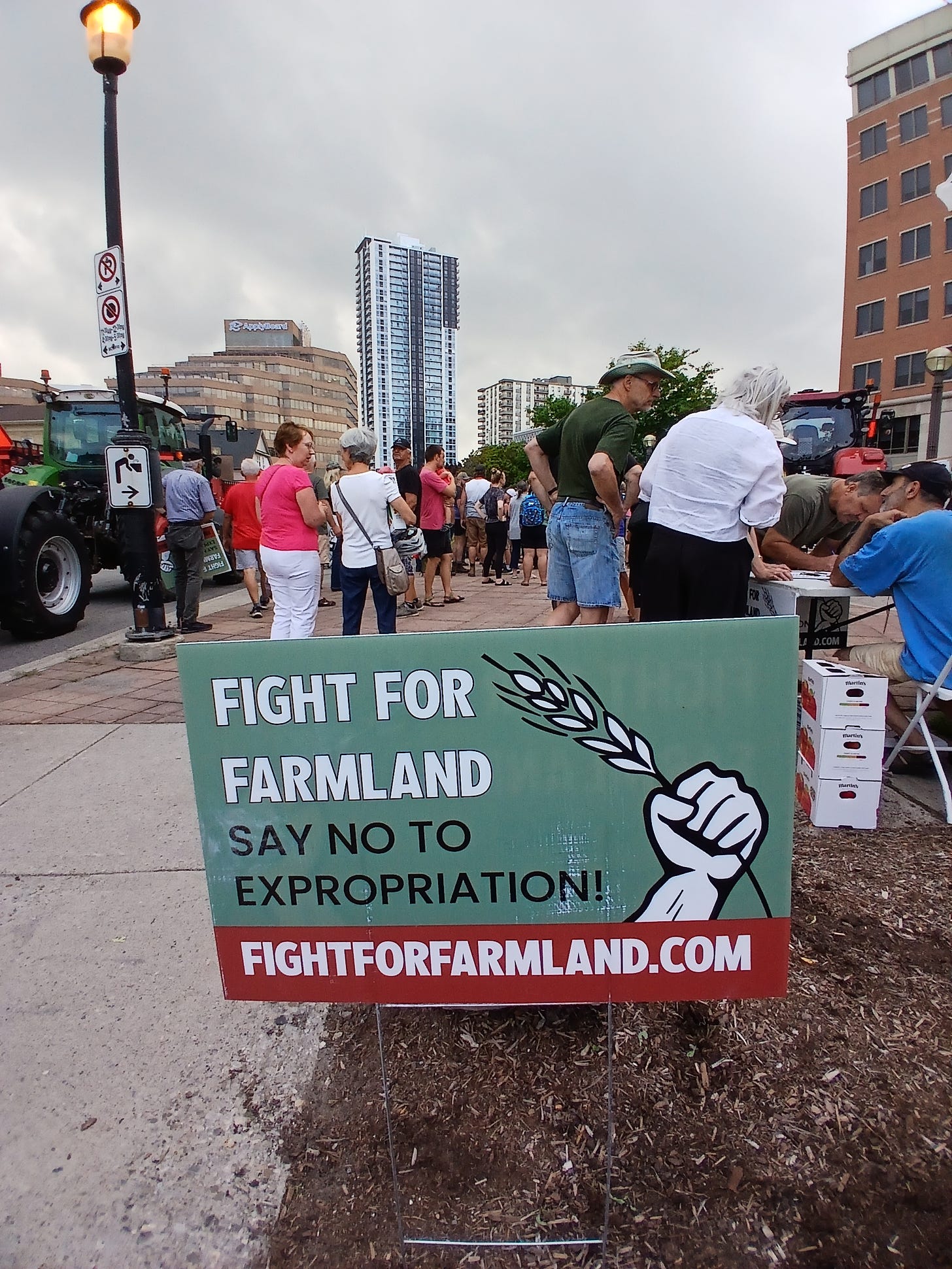 Image from the rally at 150 Frederick with a sign in front of the crowds that says Fight For Farmland Say No To Expropriation