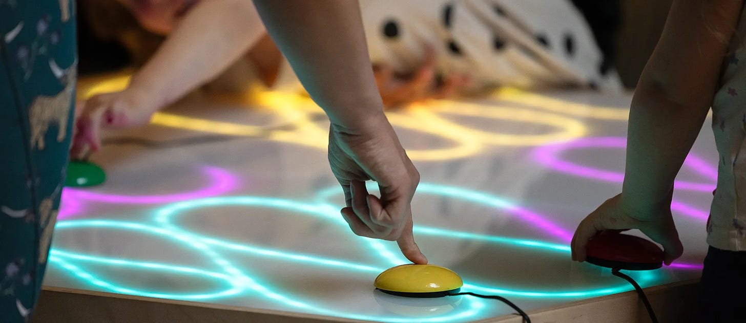 kids playing with light box, drawing swirling patterns with colourful lines