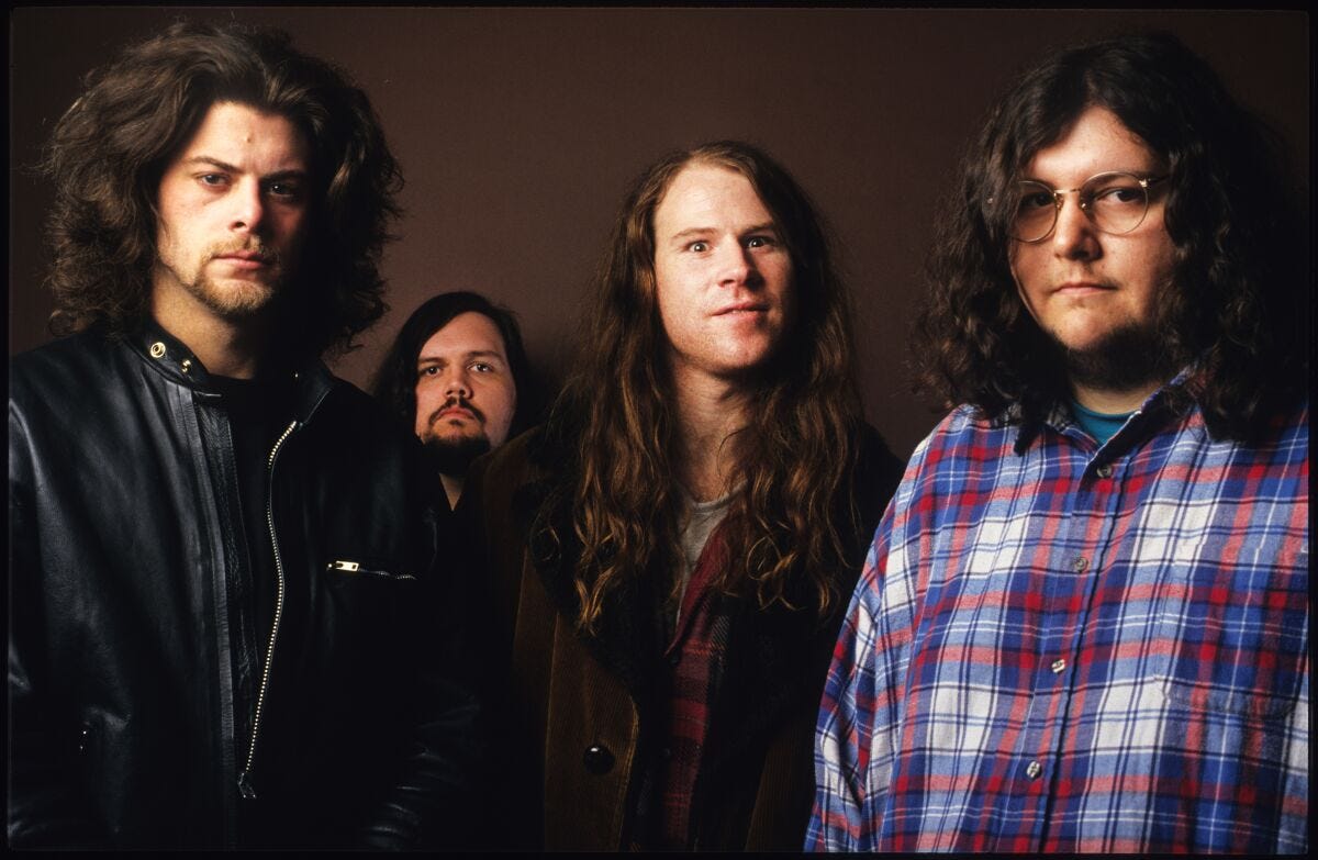 Four men with long hair pose for photos