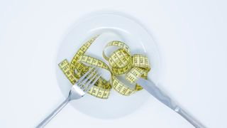 A plate with a fork, knife, and measuring tape