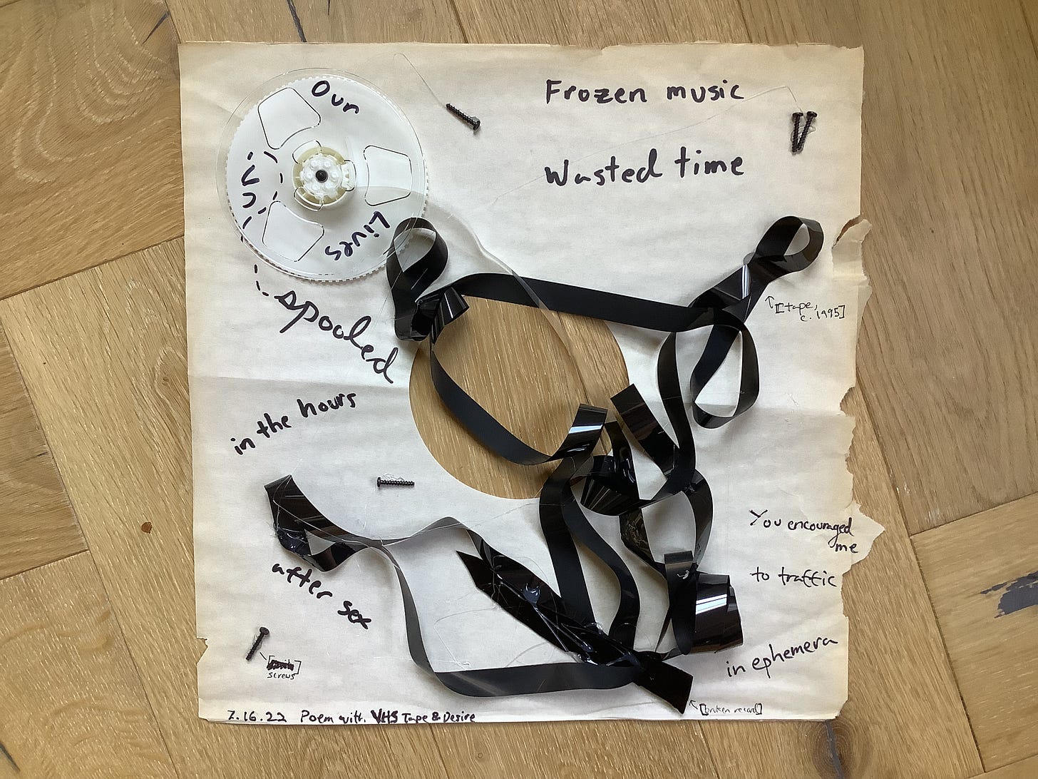 A visual poem with a VHS cassette, screws, and magnetic tape on thin paper from a record sleeve. On the left, text reads: “our lives un- / spooled / in the hours / after sex.” On the right, text reads: “Frozen music / wasted time / You encouraged me / to traffic / in ephemera.” On the bottom: “7.16.22 Poem with VHS Tape and Desire”