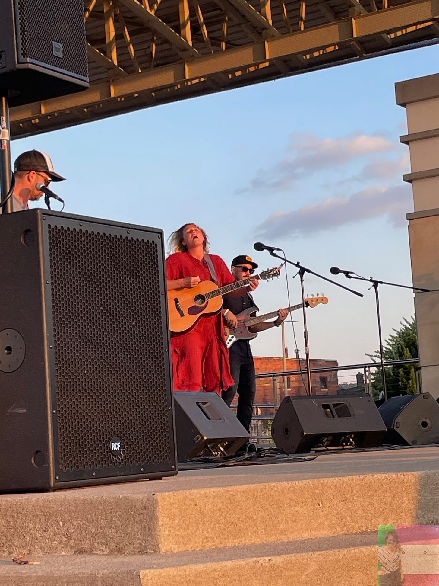 blonde woman in orange dress playing guitar and singing onstage