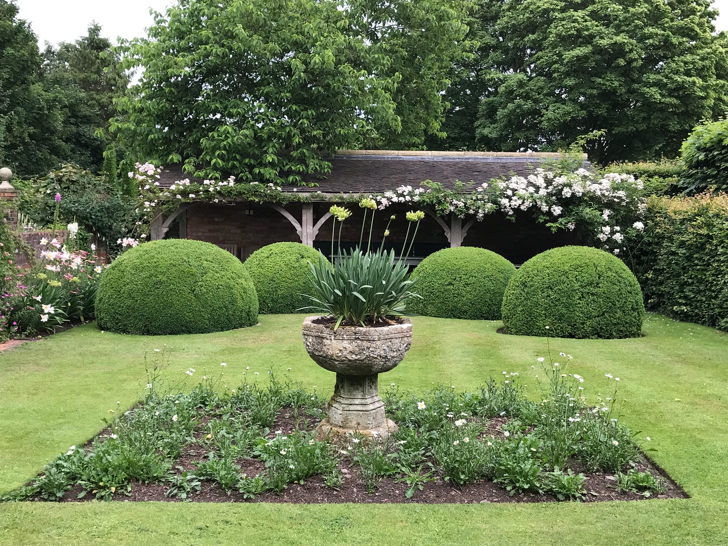 The ancient font that gives this garden its name is surrounded by loose planting in the midst of clipped and tighty box and lawns. The ancient font that gives this garden its name is surrounded by loose planting in the midst of clipped and tighty box and lawns.