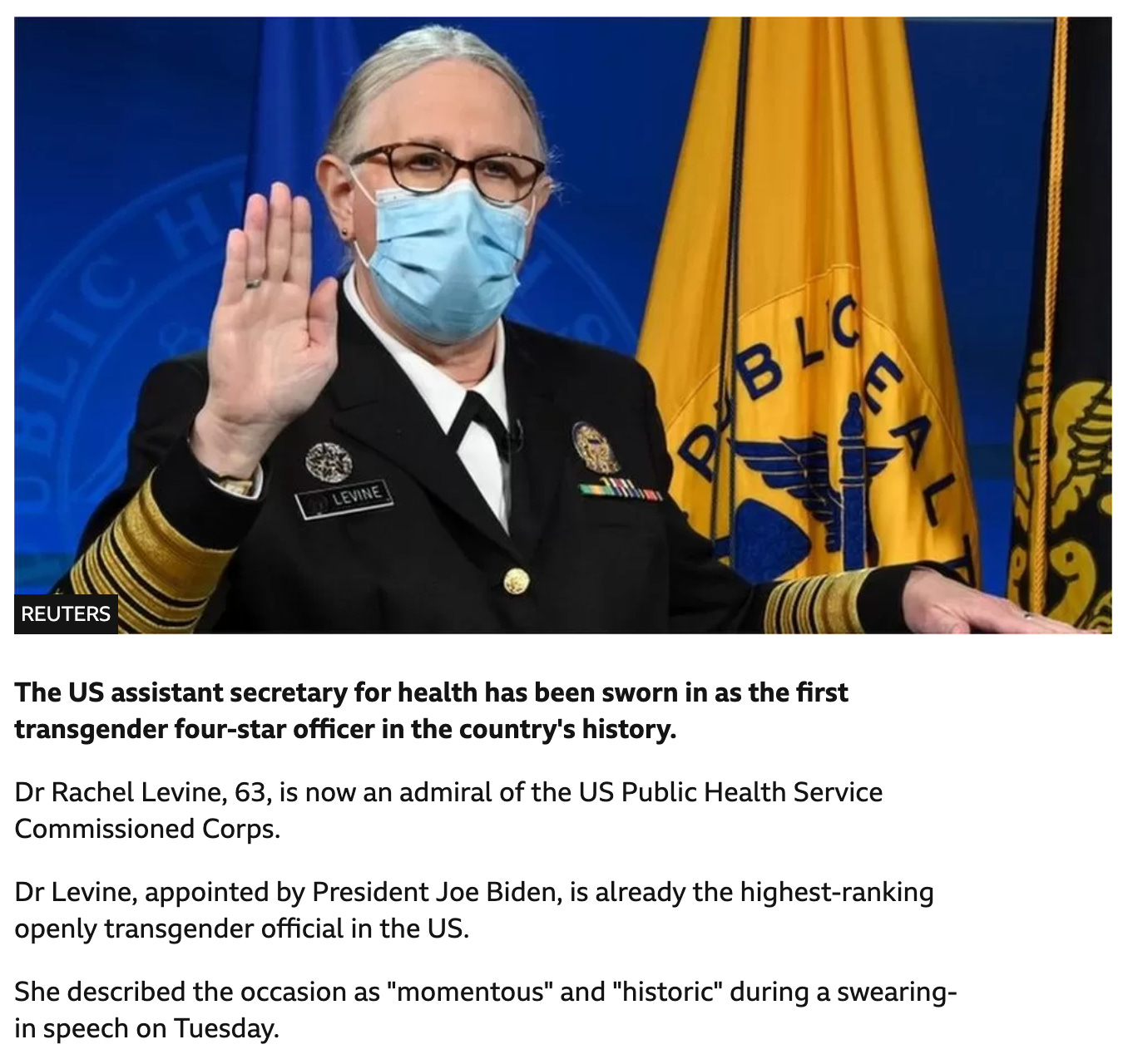 A white trans person wearing an official armed forces black uniform with gold on the cuffs and multiple medals and gold badges on the breast of the jacket. She wears a white shirt beneath and has her grey hair parted at the middle and tied back. She is wearing black rimmed glassed and a paper mask. She is holding her right hand up while her left hand in placed on a book during a swearing in ceremony. Behind her is a blue background and multiple flags of the armed forces in blue, gold, and black. Below picture is text in black font on a white background that reads:  “The US assistant secretary for health has been sworn in as the first transgender four-star officer in the country's history.// Dr Rachel Levine, 63, is now an admiral of the US Public Health Service Commissioned Corps.// Dr Levine, appointed by President Joe Biden, is already the highest-ranking openly transgender official in the US.// She described the occasion as "momentous" and "historic" during a swearing-in speech on Tuesday.”