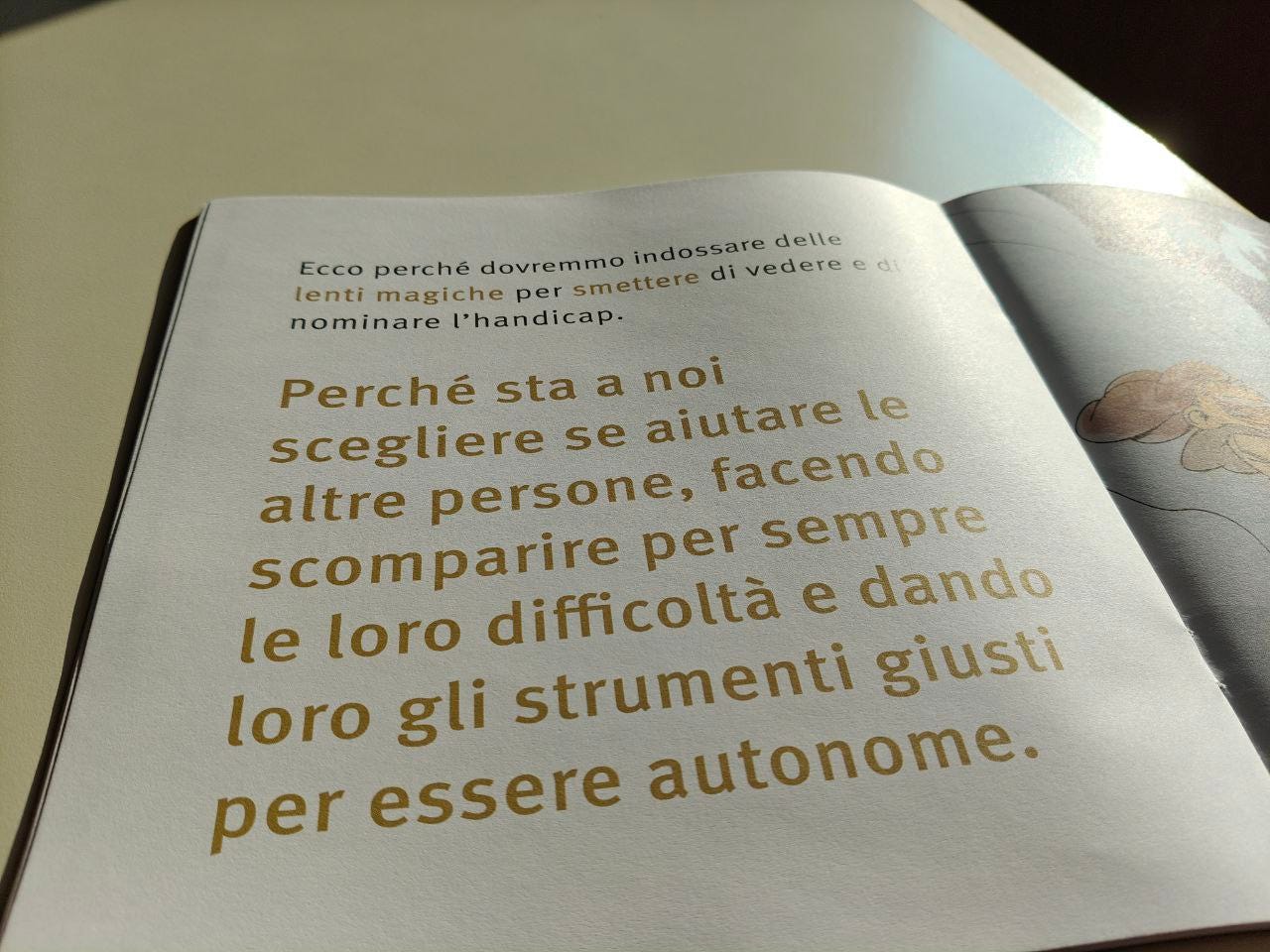 Una pagina della parola HANDICAP delle Scatoline di effequ, con questa scritta: "Perché sta a noi scegliere se aiutare le altre persone, facendo scomparire per sempre le loro difficoltà e dando loro gli strumenti giusti per essere autonome". La pagina è appoggiata su un tavolo di legno bianco sporco e nell'angolino in alto a destra si intravede un pezzetto di muro in ombra.