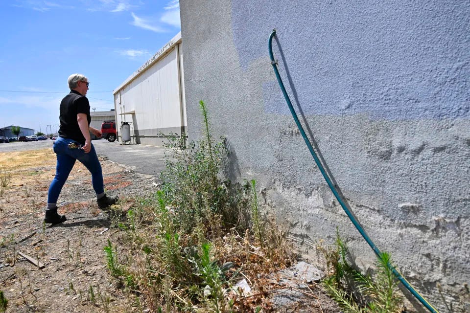 Code enforcement officer Jesalyn Harper walks past the garden hose which tipped her off to an illegal medical lab owned by Chinese business people that was operating inside an old warehouse in Reedley, Calif., on Aug. 1, 2023. (Eric Paul Zamora/The Fresno Bee via AP)