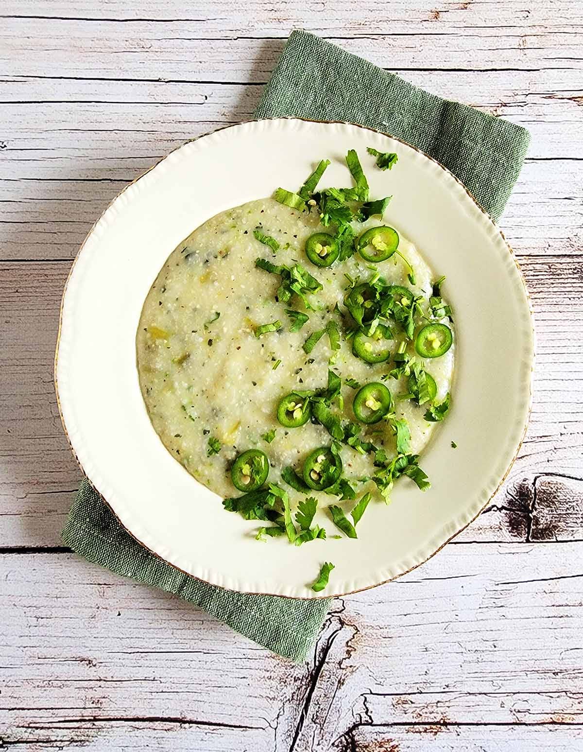 A bowl of green chile grits on a wooden table. 