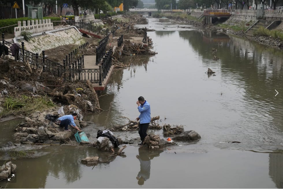 Two men try to salvage something from the mud and water in the Mentougou district of Beijing.